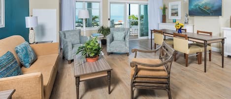 A spacious living room with a sofa, armchairs, a coffee table, and a dining area with a table and chairs.