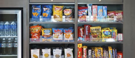 Máquina expendedora llena de botanas y bebidas, incluyendo Doritos, Lay's y Mountain Dew.