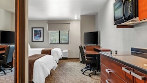 Une chambre d’hôtel avec deux lits, un bureau, une chaise, un four à micro-ondes et une télévision.