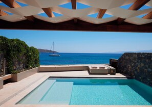 A pool area with a view of the sea and a sailboat. - Elounda Peninsula Luxury Resort (Agios Nikolaos)