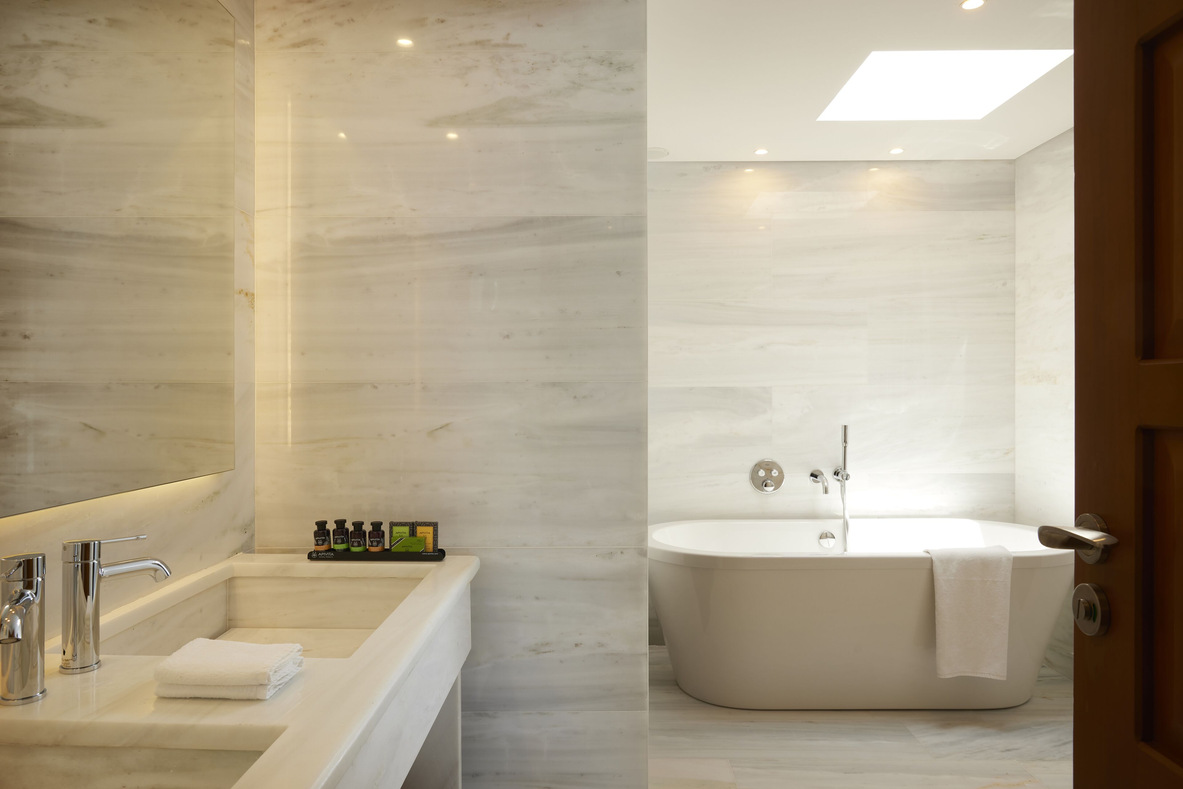 A modern bathroom with a large mirror, a sink, and a freestanding bathtub.
