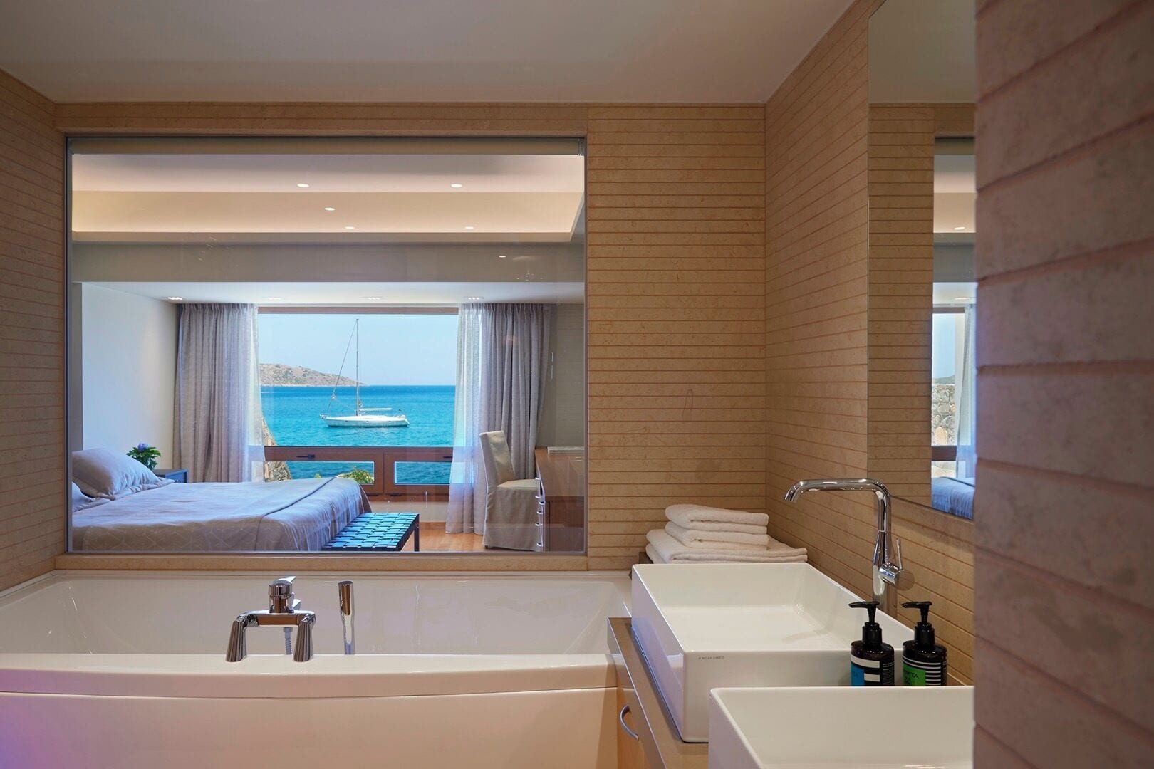 Un baño moderno con una bañera grande, dos lavamanos y vista al mar.