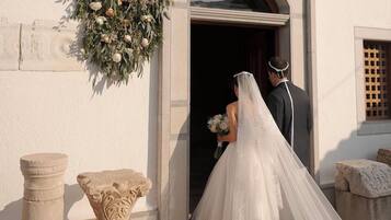 A wedding couple exiting a building with a floral decoration above the entrance.