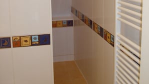 A bathroom with white walls, a tiled floor, and a towel rack.