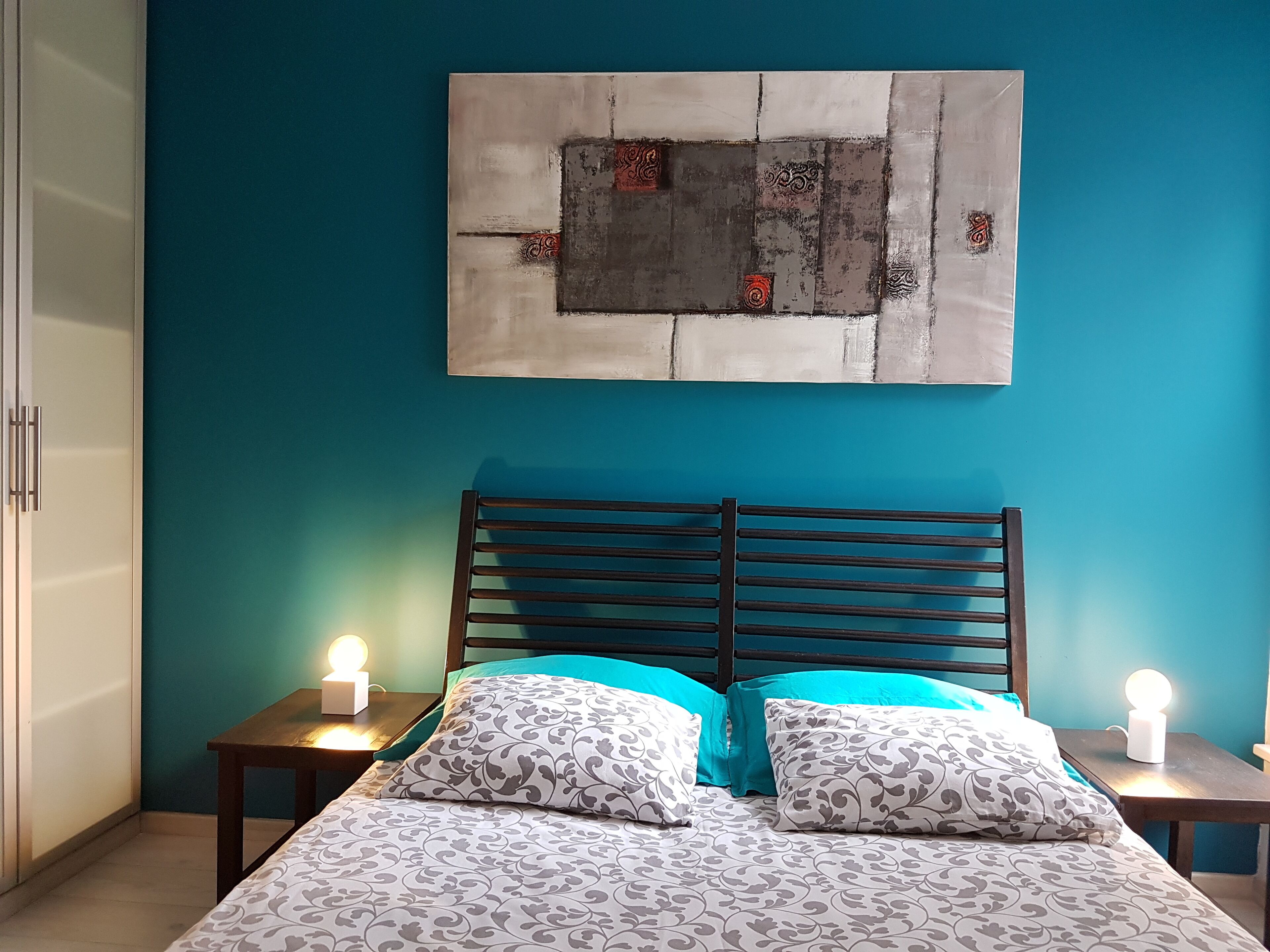 Une chambre à coucher comprenant un lit, deux tables de chevet et une œuvre d’art accrochée au mur.