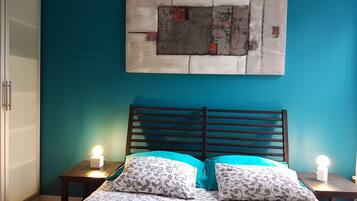 Une chambre à coucher comprenant un lit, deux tables de chevet et une œuvre d’art accrochée au mur.