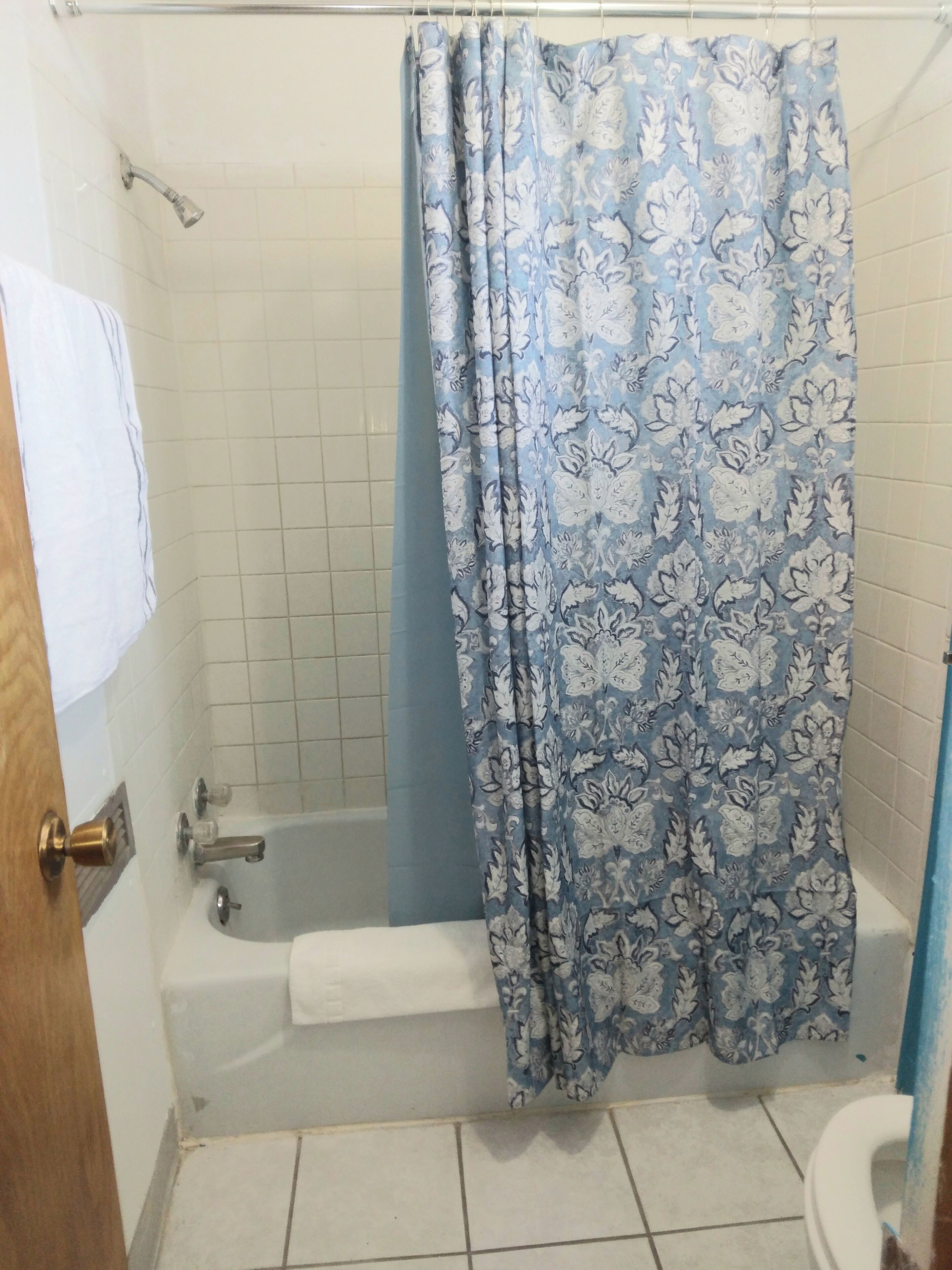 A bathroom with a bathtub, a shower curtain, and a toilet.