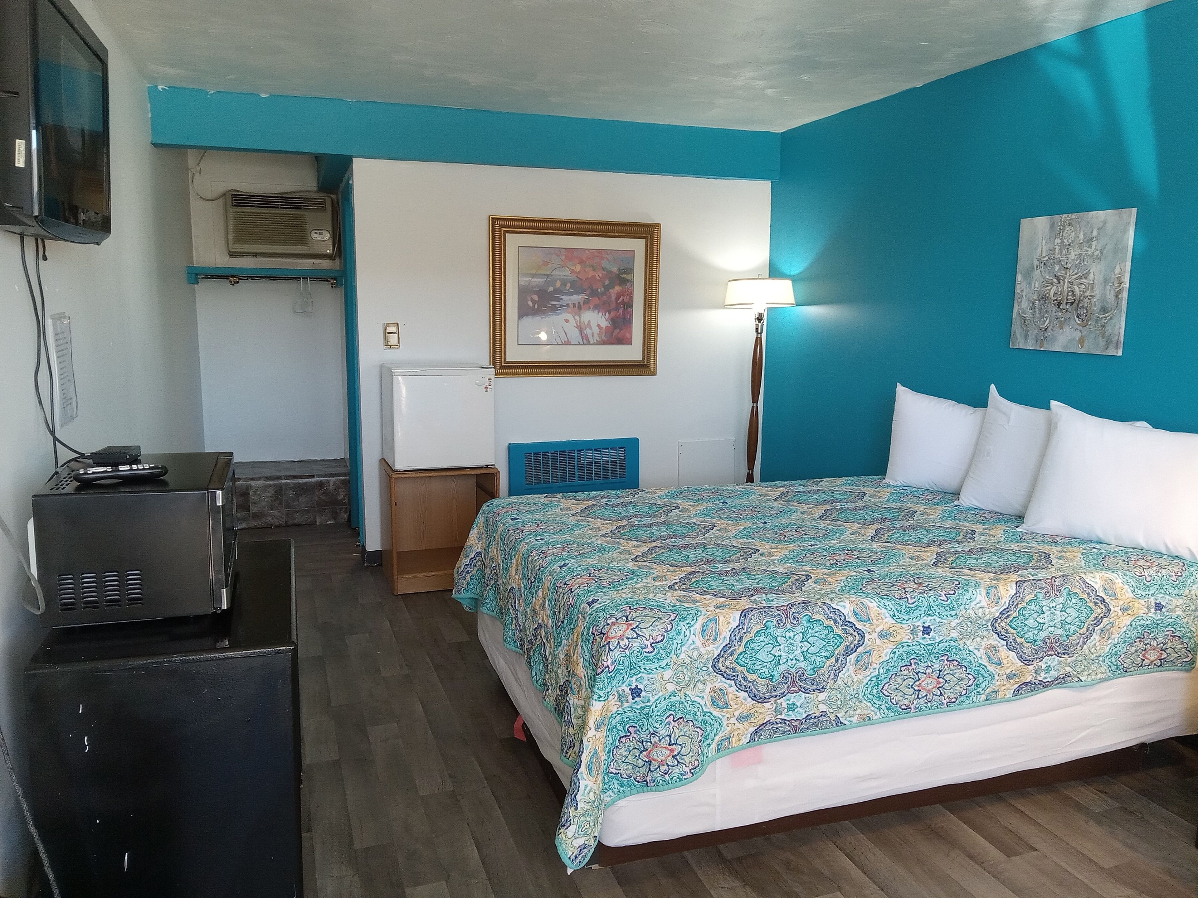 Habitació d'hotel amb un llit, escriptori, televisió i nevera.