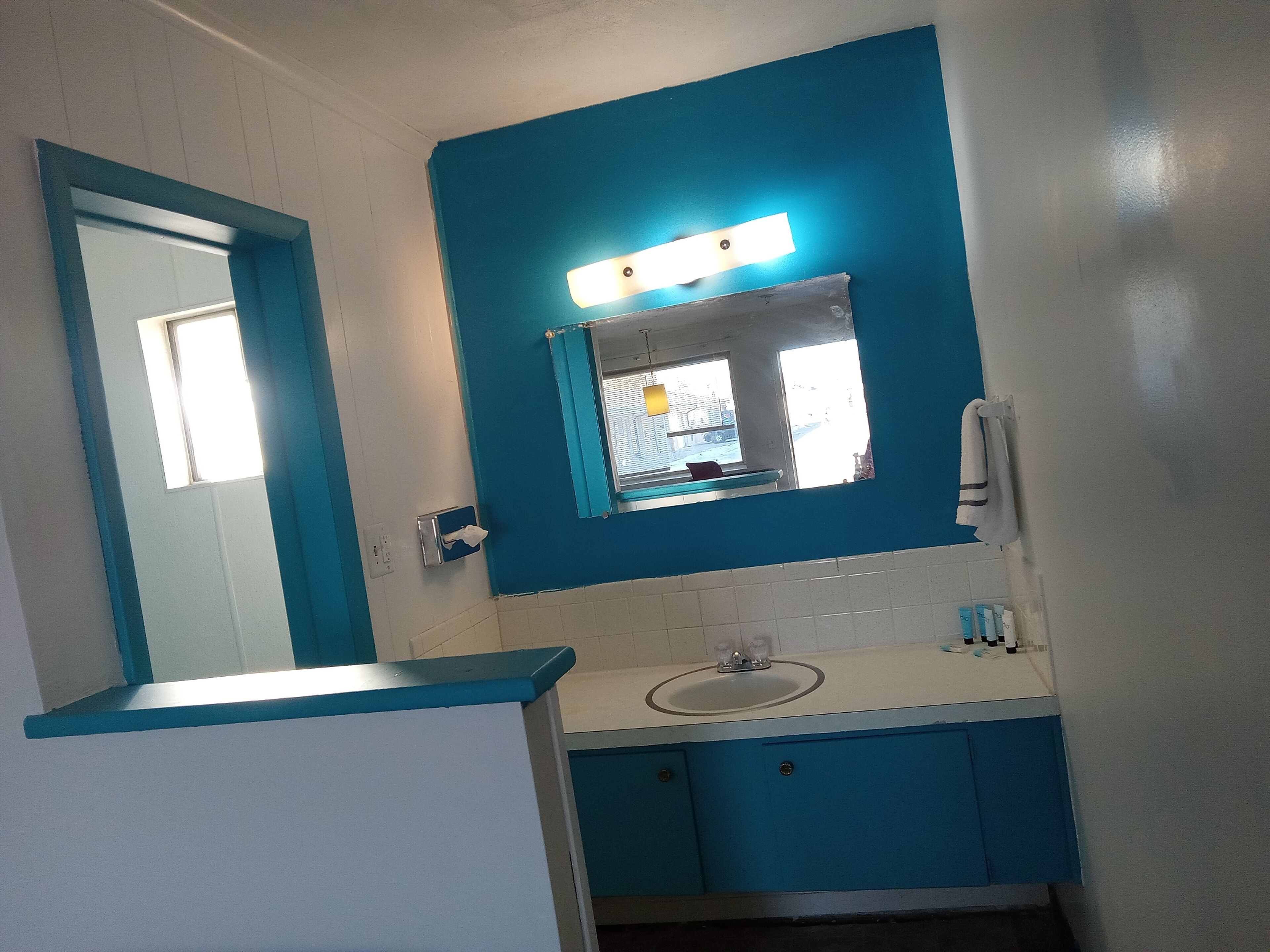 Une salle de bain avec un mur d’accent bleu, un miroir, un lavabo et une serviette accrochée au mur.