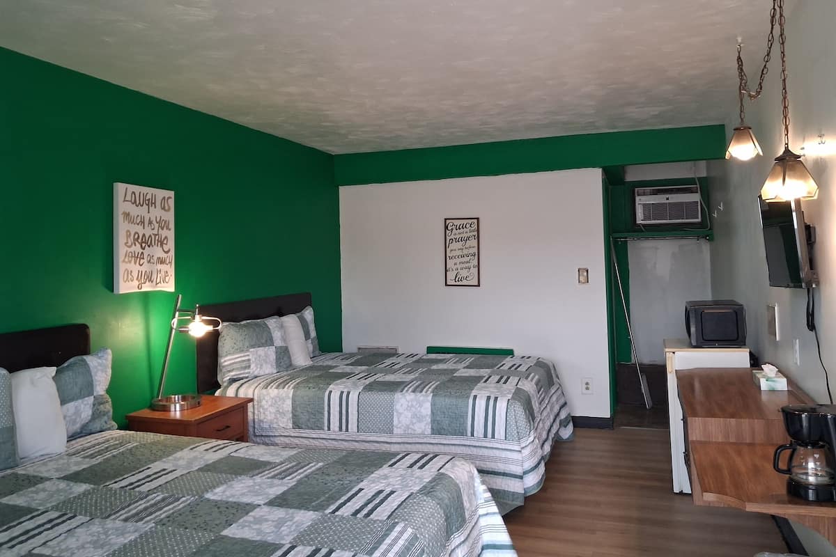 Une chambre avec deux lits, un bureau équipé d’une machine à café, une lampe et des affiches motivantes accrochées aux murs.
