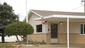 A single-story building with a covered entrance and a small tree in front. - Capri Motel (Scottsbluff)