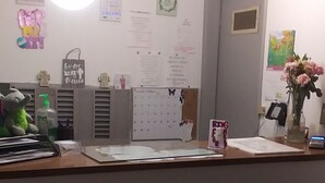 A reception desk with a calendar, a small plant, and a decorative elephant. - Capri Motel (Scottsbluff)