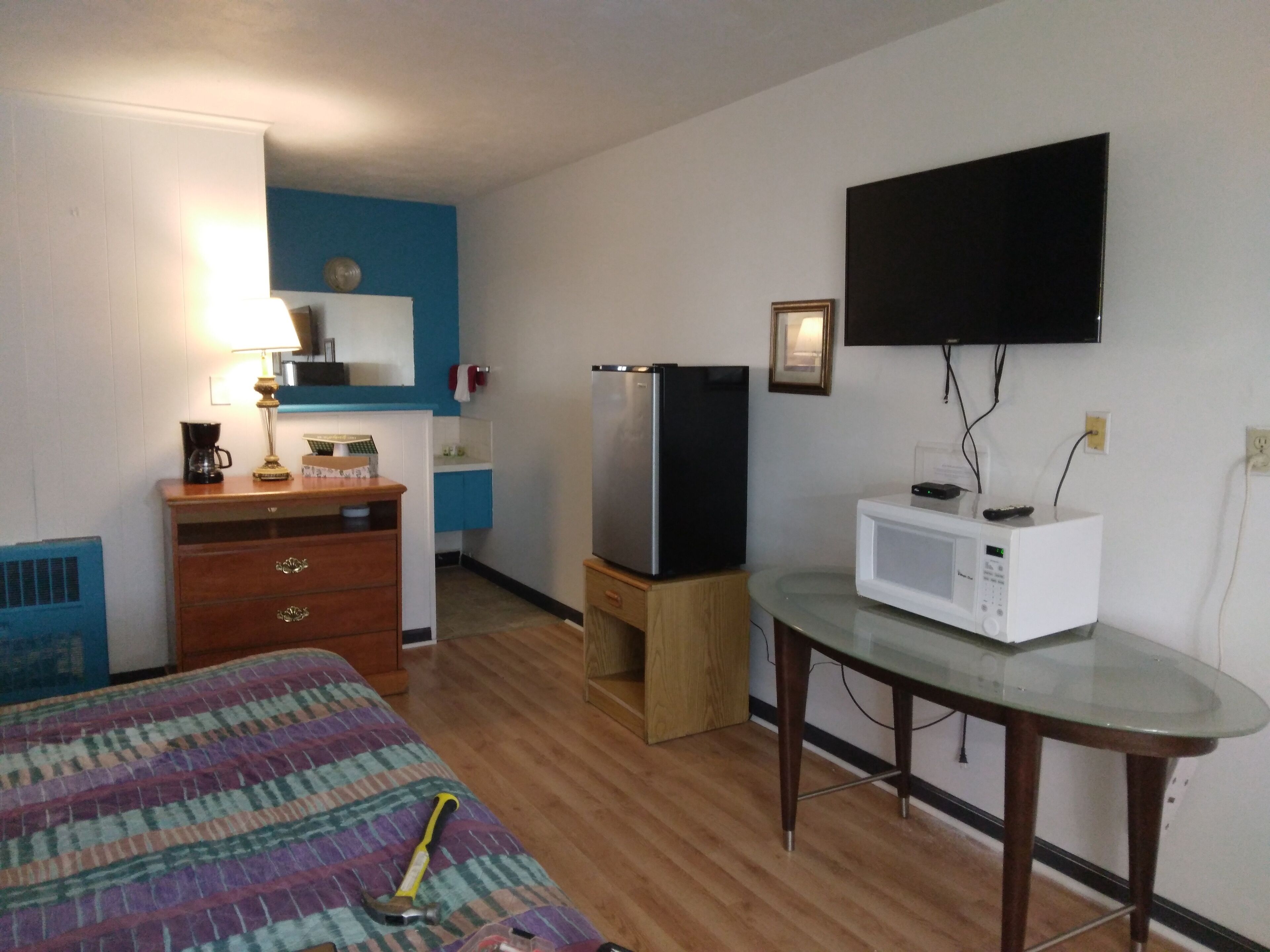 Camera d'albergo compatta con un letto, un tavolino, un forno a microonde, un frigorifero, una TV e un comò.