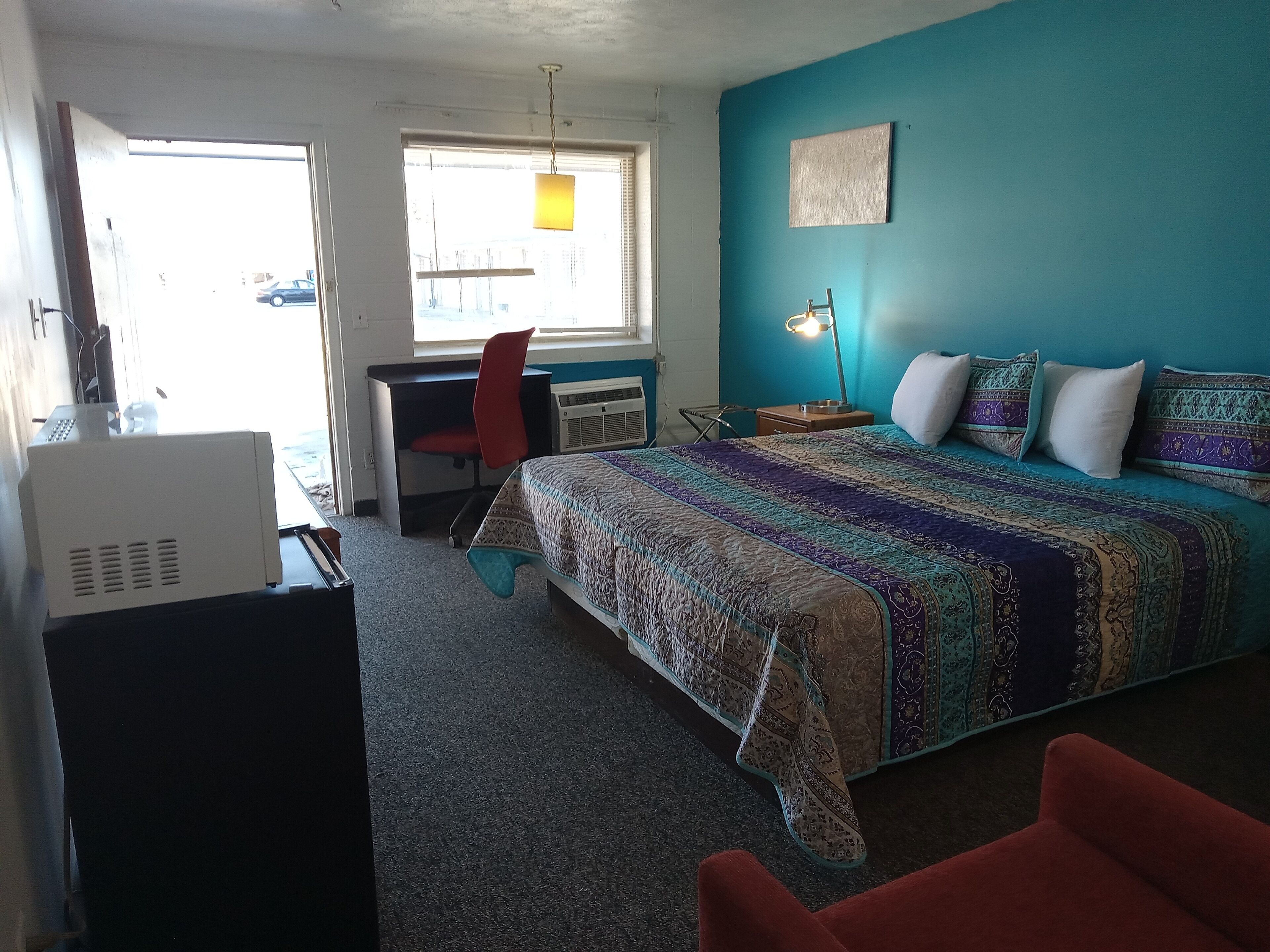 A bedroom with a bed, desk, chair, and a heater.