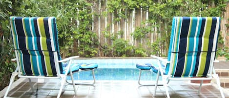 Una piscina al aire libre, sillones reclinables de piscina
