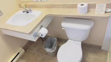 Un baño con lavamanos, inodoro y cubo de basura.