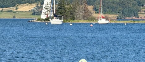 A lighthouse with a red top, surrounded by calm water and boats.