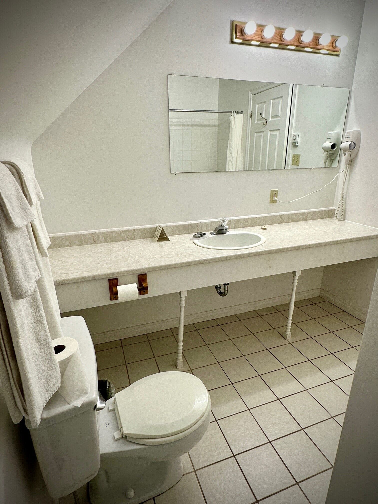 A bathroom with a toilet, sink, mirror, and vanity.