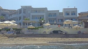 Un hôtel situé en bord de mer, doté de nombreux balcons, d’un espace extérieur aménagé et de parasols.