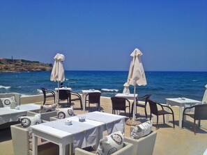 An outdoor seating area with tables and chairs, overlooking the sea. - Filoxenia Beach (Rethymno)