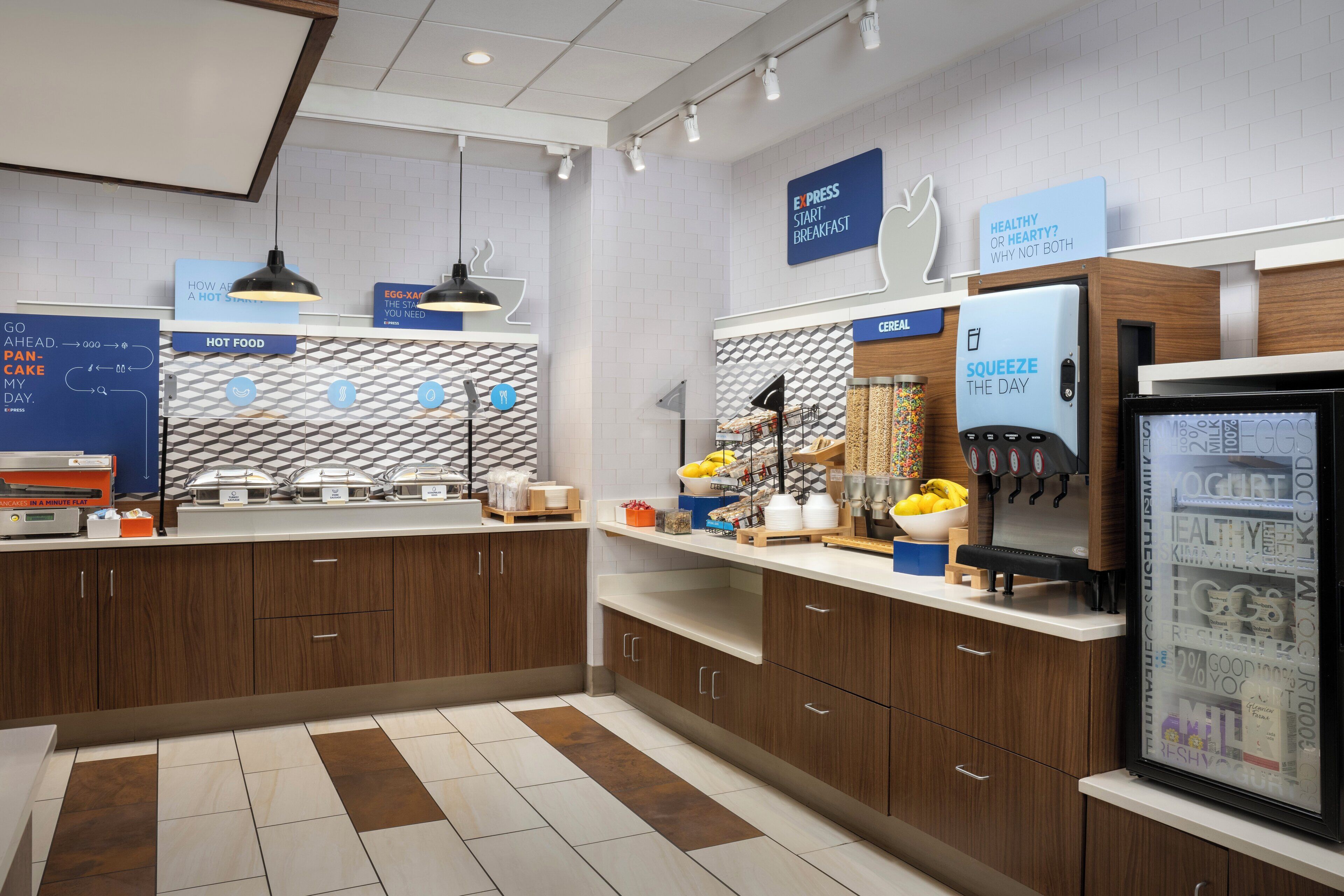 A modern kitchen with a breakfast bar, a refrigerator with a yogurt dispenser, and a sign indicating a breakfast option.