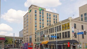 A hotel with a prominent sign, multiple floors, and a street view with vehicles and pedestrians.