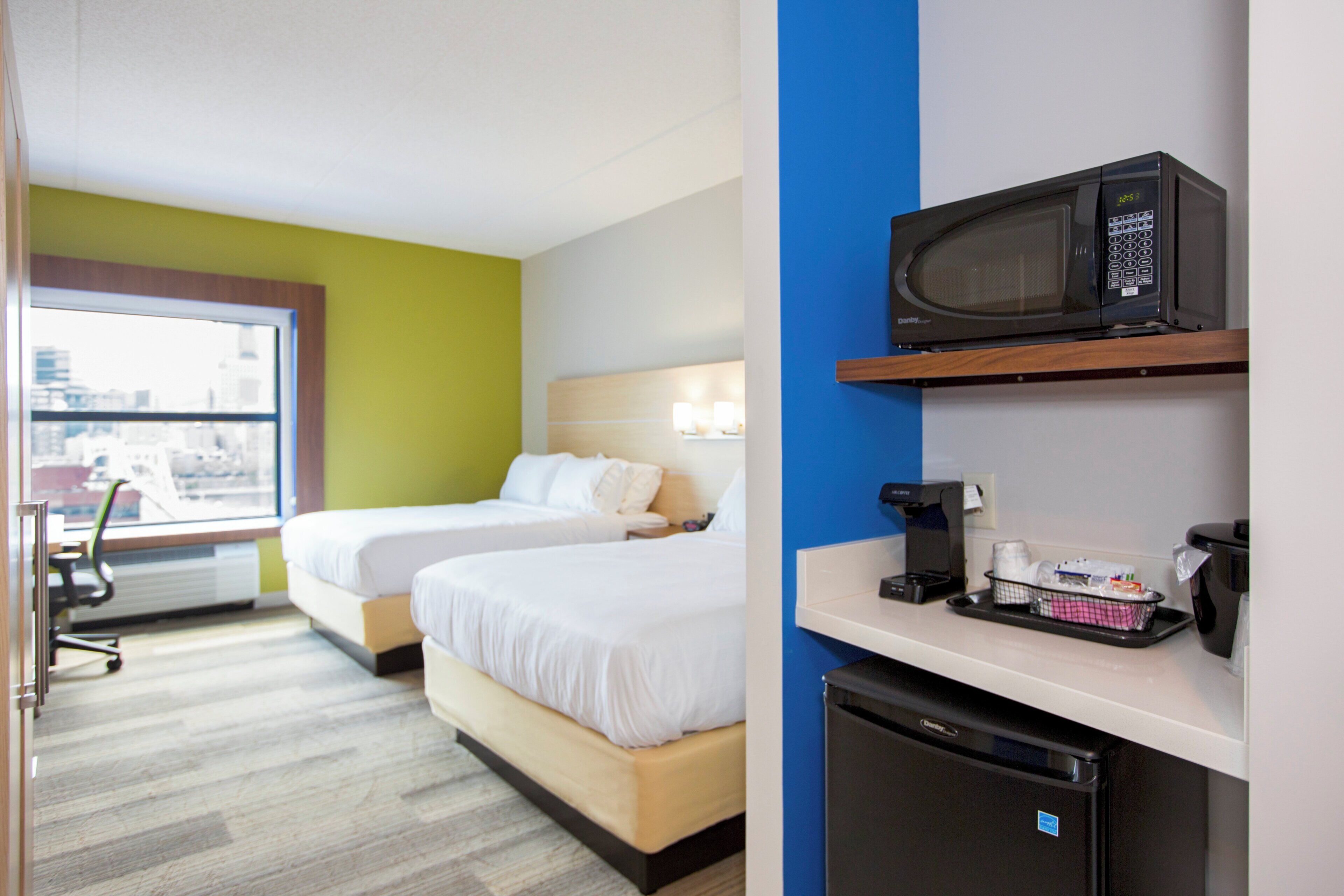 Une chambre d’hôtel avec deux lits, un four à micro-ondes, une machine à café et un petit réfrigérateur.