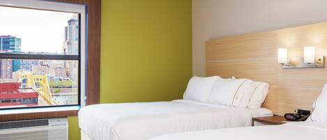 A hotel room with two beds, a window with a view of a cityscape, and a wall-mounted light fixture.