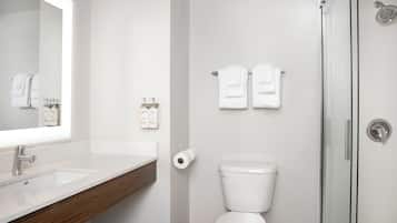 A modern bathroom with a white sink, a toilet, and a glass-enclosed shower.