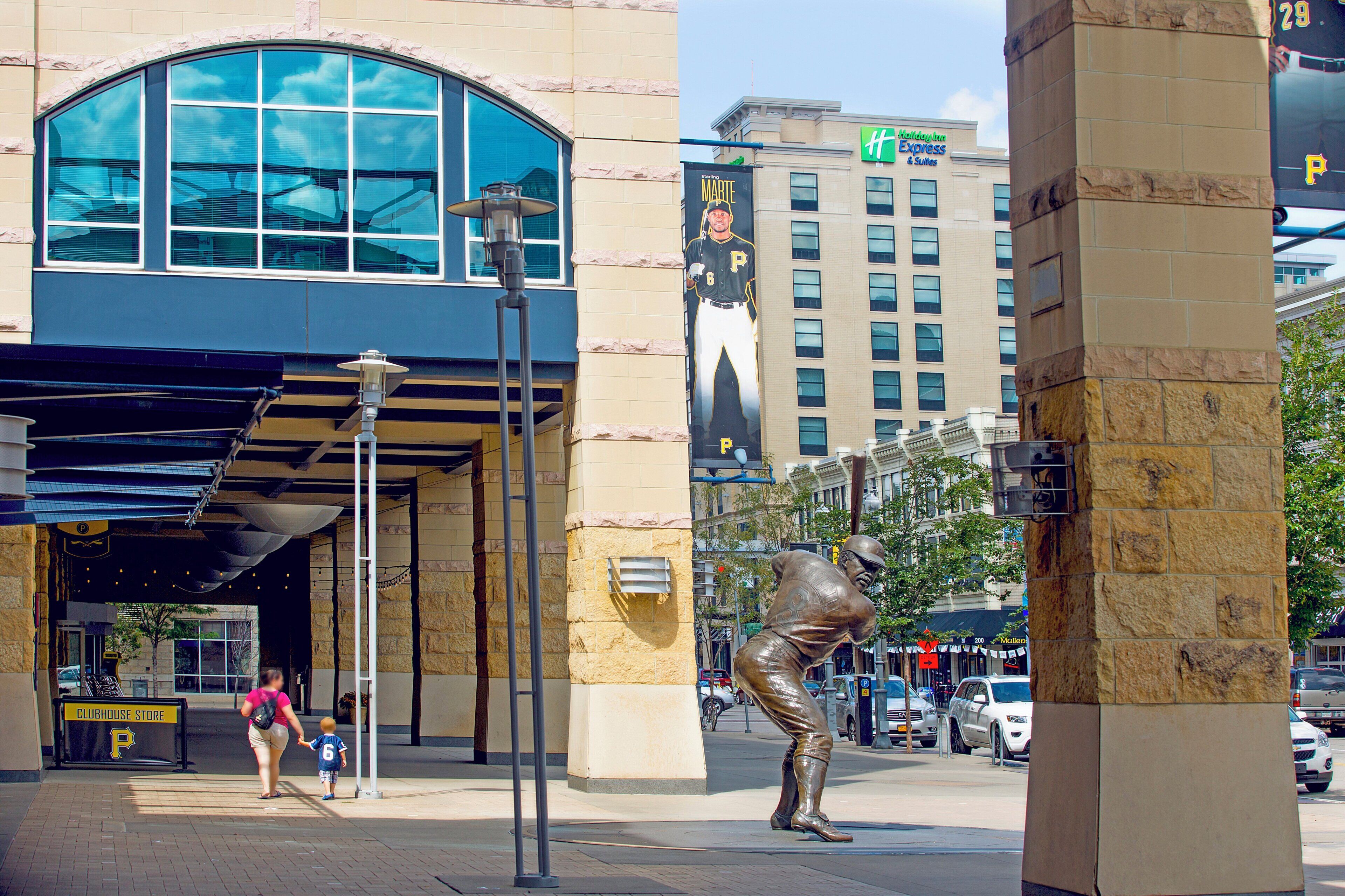 Ein Gebäude mit großem Glasvorsprung, einer Straßenlaterne und einer Statue eines Baseballspielers.
