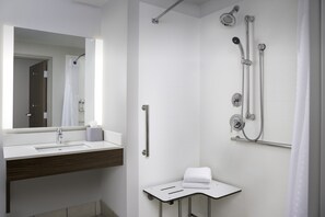 Ein modernes Badezimmer mit Waschbecken, Spiegel und Duschbereich in Weiß.