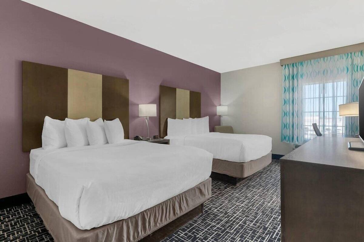 Una habitación de hotel con dos camas, un escritorio y una ventana con cortinas.