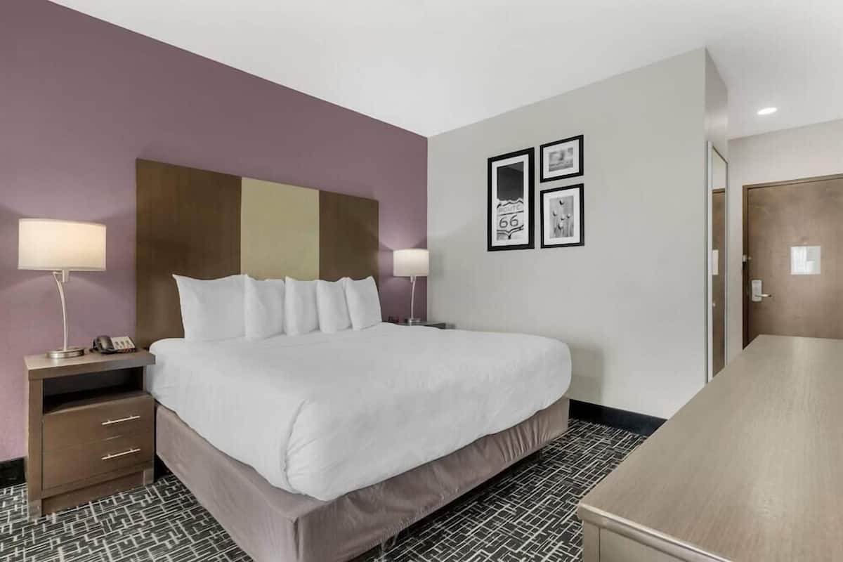 Una habitación de hotel con cama, mesitas de noche, escritorio y puerta.