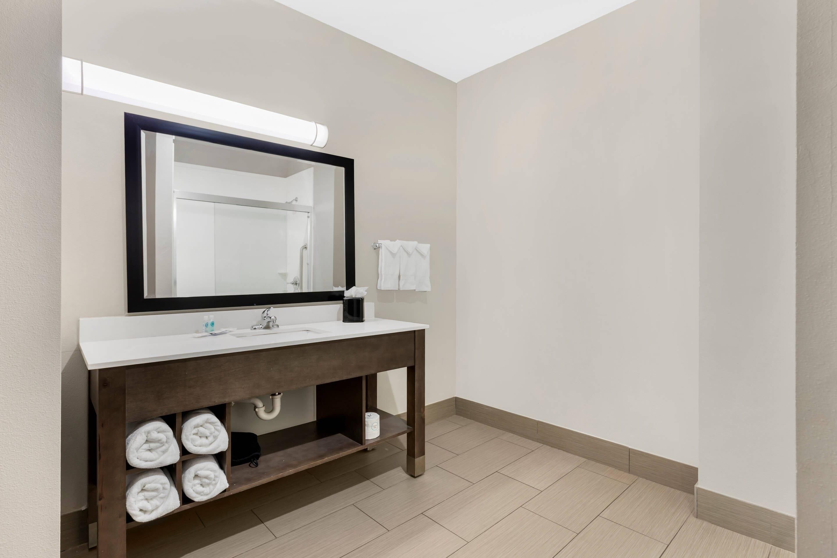 A modern bathroom with a white sink, dark wooden vanity, and a large mirror.