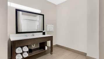 A modern bathroom with a white sink, dark wooden vanity, and a large mirror.