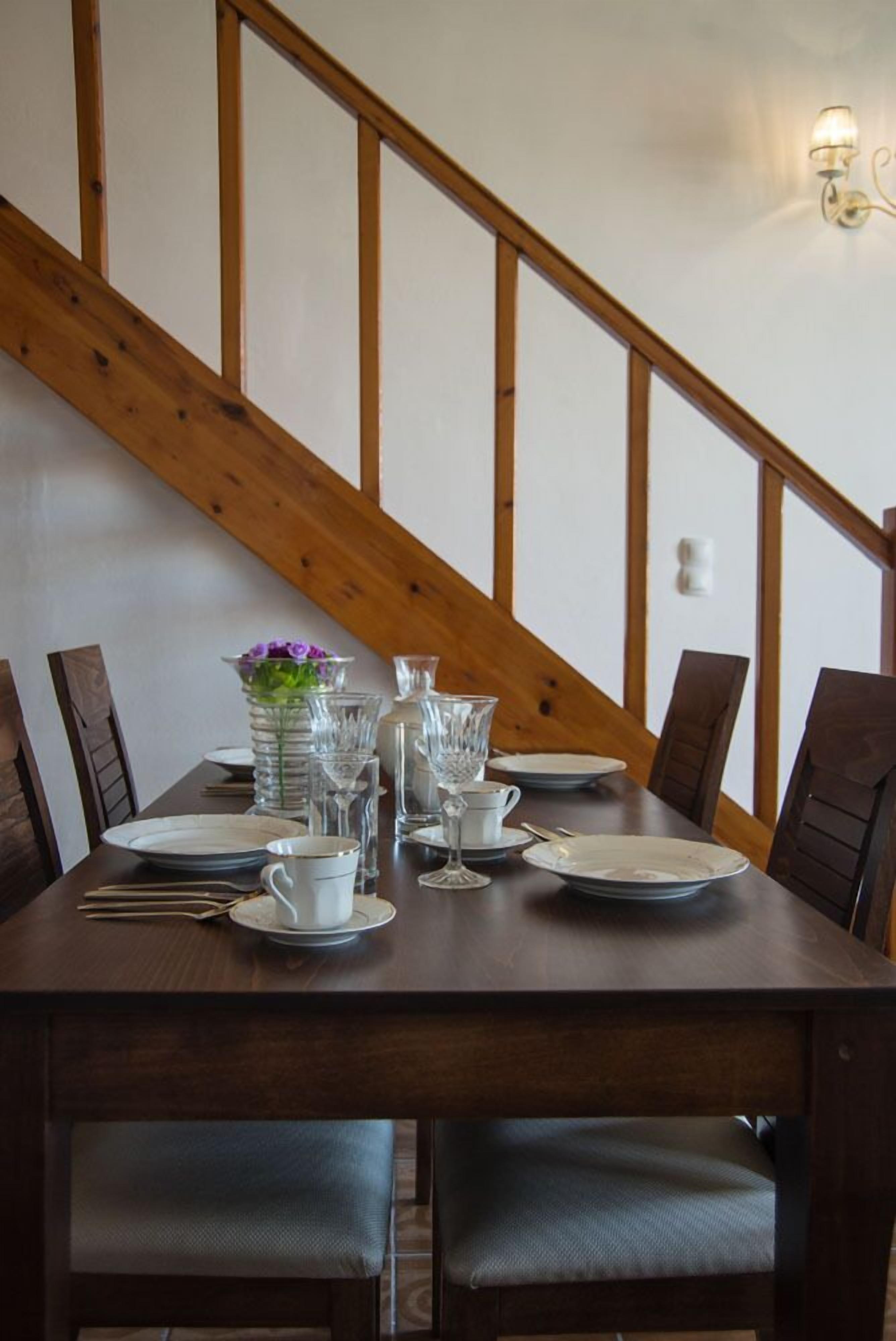 A dining table set with plates, glasses, and a vase of flowers.