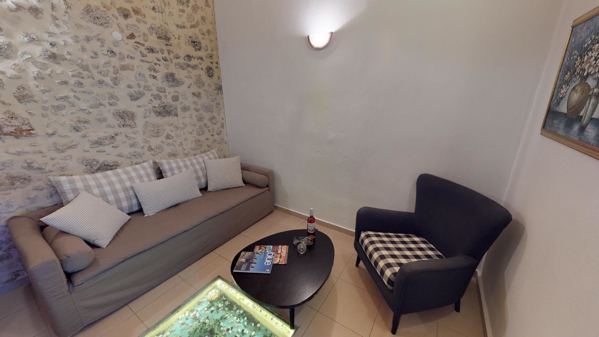 A living room with a sofa, armchair, coffee table, and a wall-mounted light fixture.