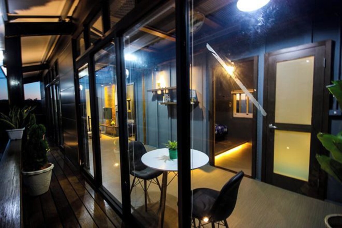 A modern interior with a glass partition, a round table with chairs, and a staircase leading to another level.