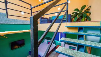 Habitación con literas, televisión, planta y escalera.