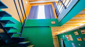 A multi-level interior with wooden beams, a green wall, and a staircase. - Oasis Inn (Hengchun)