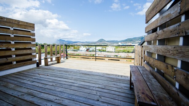 A wooden deck with benches overlooking a cityscape and mountains. - Oasis Inn (Hengchun)