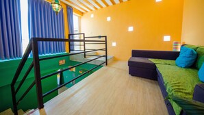 A room with a bunk bed, a sofa, a green carpet, and a window with blue curtains. - Oasis Inn (Hengchun)