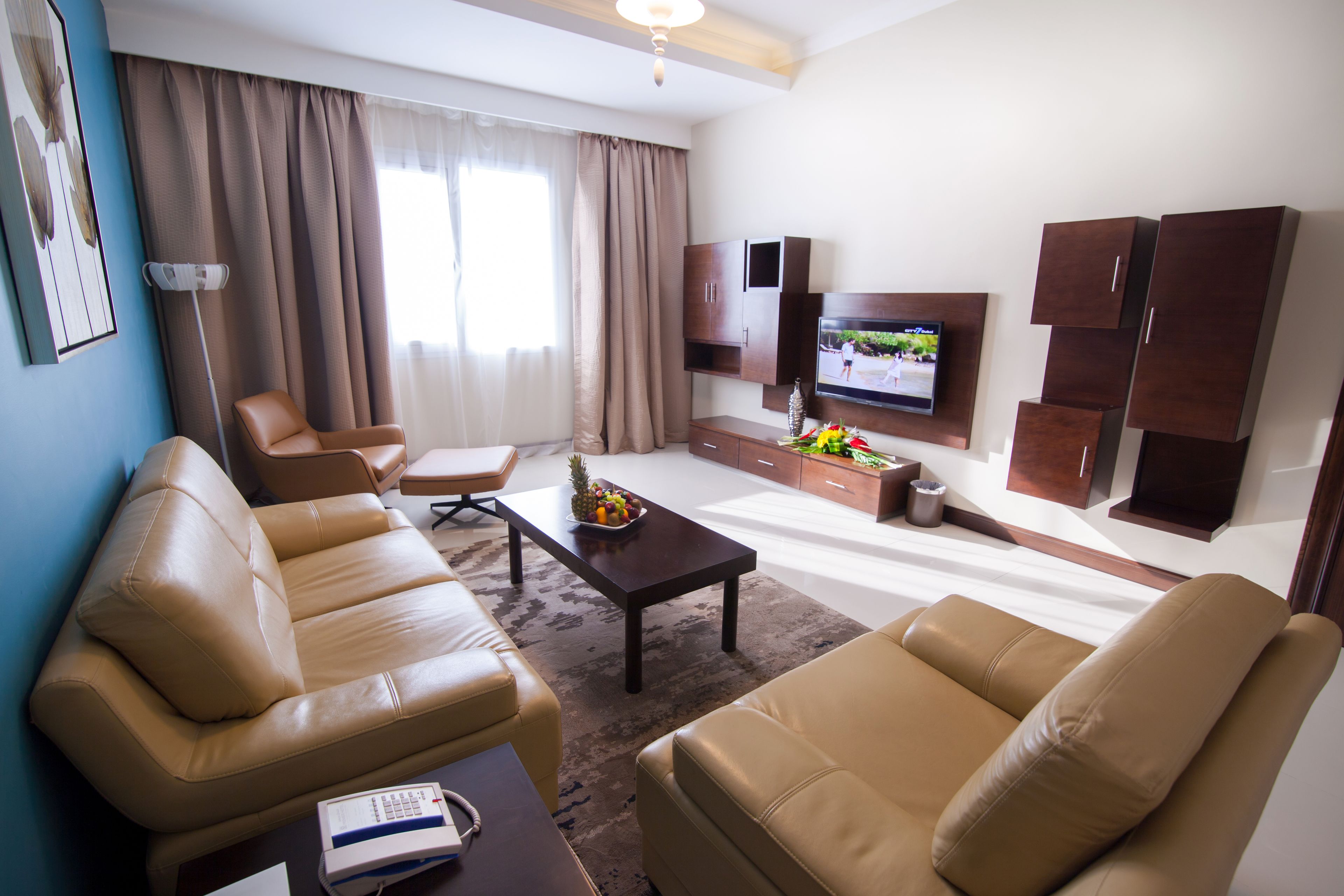 A living room with leather sofas, a coffee table, a TV, and a cabinet.