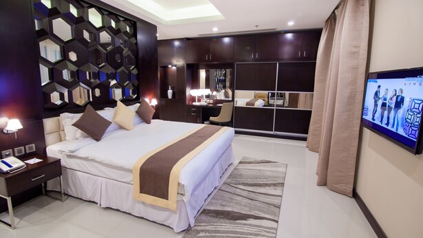 Une chambre d’hôtel moderne équipée d’un grand lit, d’un bureau, d’une télévision et d’une armoire.