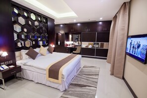 Una habitación de hotel moderna con una cama grande, un escritorio, un televisor y un armario.