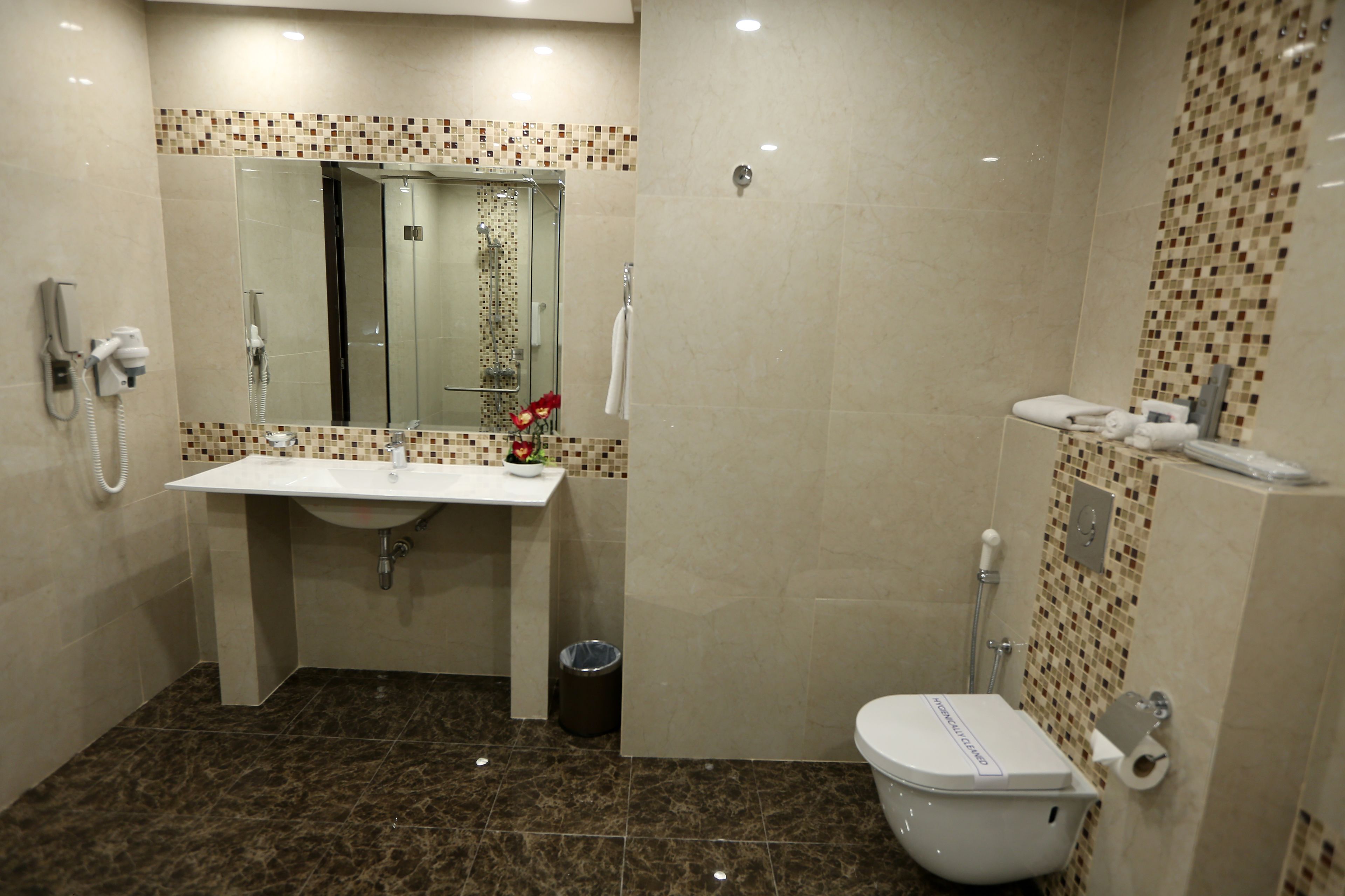 Une salle de bain équipée d’un lavabo, d’un miroir, d’une douche, de toilettes et d’une poubelle.