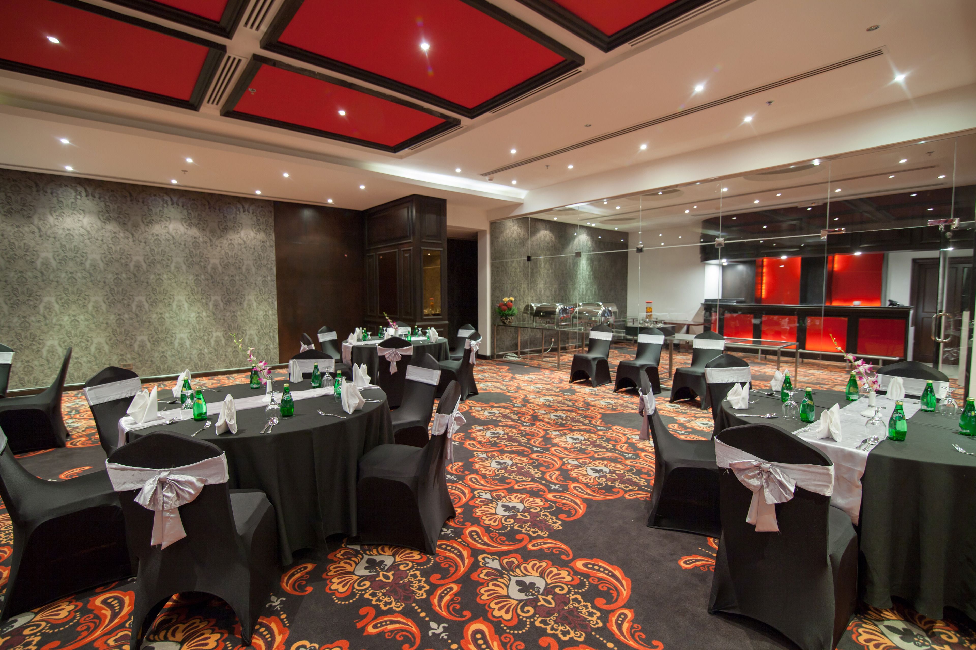 A conference room with round tables, black chairs, and a patterned carpet.