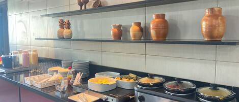 Una cocina con múltiples estantes que exhiben cerámica, un bufé con diversos platos y una estufa.