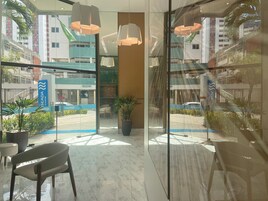 Un vestíbulo de hotel con pared de vidrio, modernas lámparas colgantes, una zona de estar y vistas a la calle y edificios.