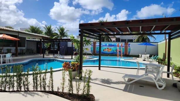 A swimming pool area with lounge chairs and a covered seating area. - Hotel Enseada dos Corais (Cabo de Santo Agostinho)